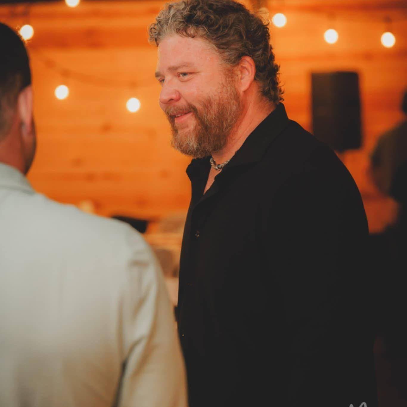 Ryan Neal, founder of OrangeHat, speaking with a guest at an event.